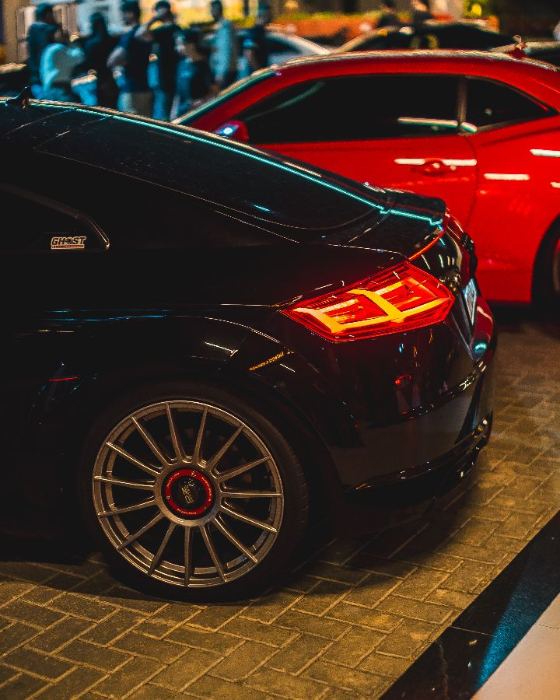 Audi TT preto ao lado de um carro vermelho